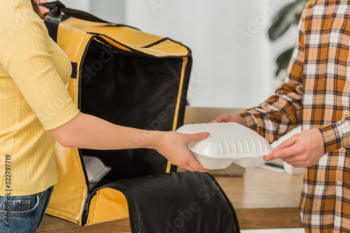 Cropped view of courier with thermo bag giving takeaway food to businessman photo