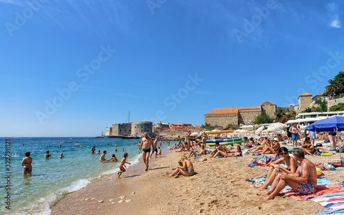 Fototapeta Naklejka Na Ścianę i Meble -  People on beach in Adriatic Sea and Dubrovnik fortress