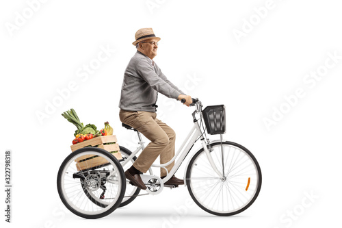 Mature man riding a crate with fruits and vegetables on a tricycle