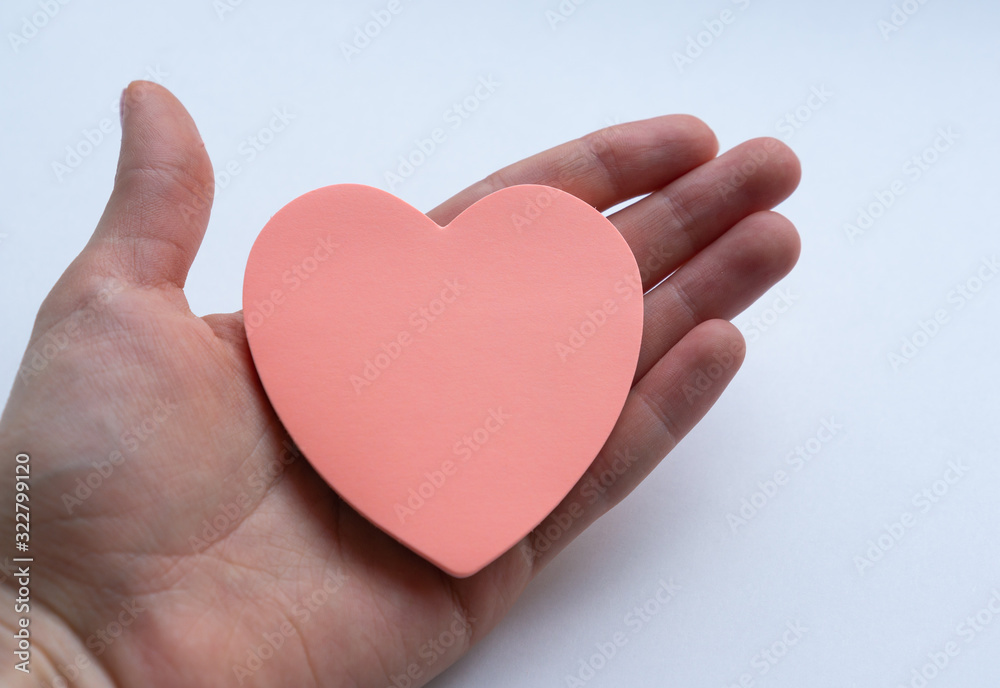 Woman's hand holding pink heart-shaped sticky notes on white background. Concept of love, minimalism. Woman's hand holding pink heart-shaped sticky notes on white background. Concept of love, minimalism.