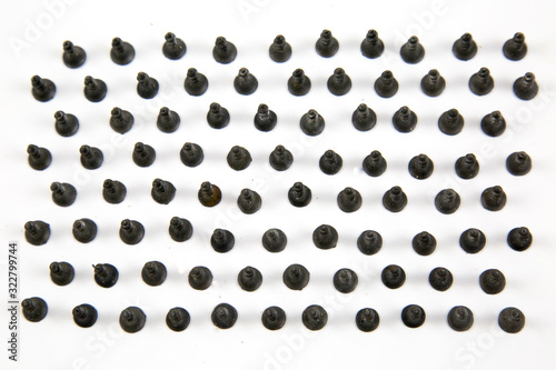 Fototapeta Naklejka Na Ścianę i Meble -  Small black wood screws (bedbugs) lined up in rows, isolated on a white background, the idea is the concept of free space for text.  Construction, repair, fasteners.