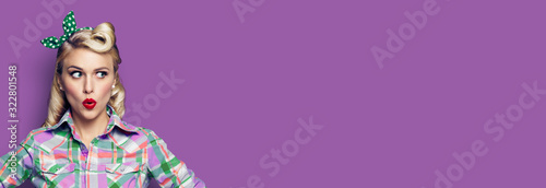 Portrait of excited surprised woman. Girl in pin up style, looking sideways. Retro fashion and vintage concept. Violet purpure color background. Copy space for some text.