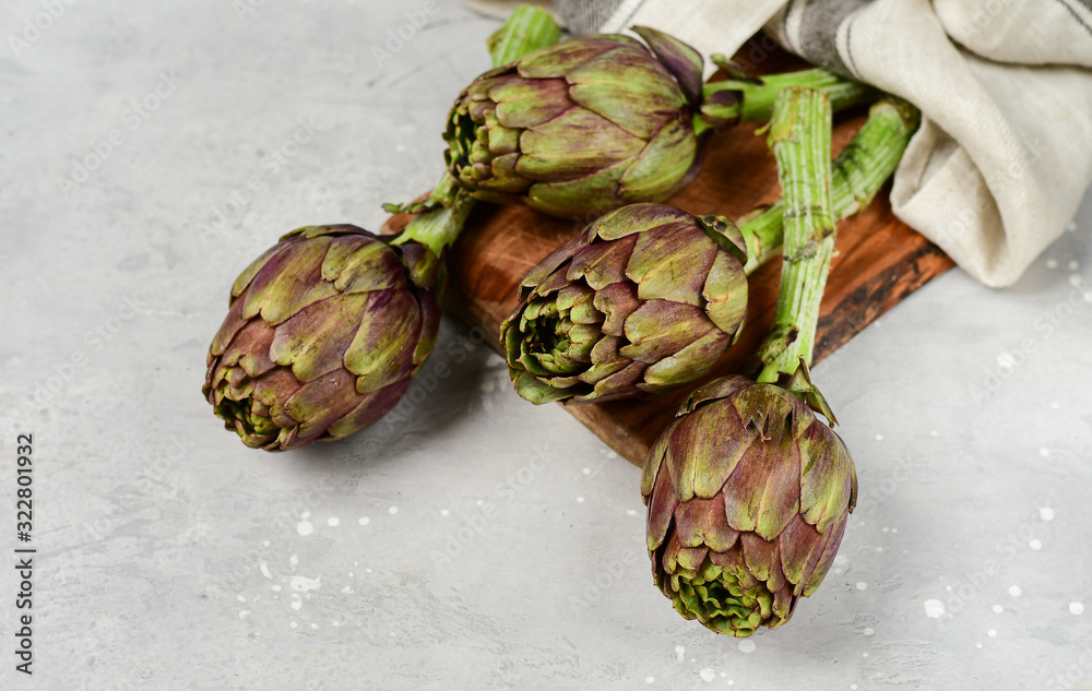 Fototapeta premium Fresh artichokes on a light stone table. . organic seasonal vegetables. artichoke recipe. selective focus
