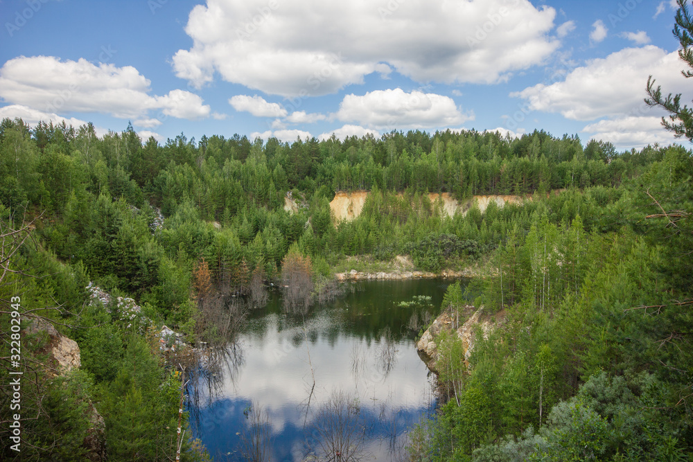 Fototapeta premium Flooded emerald quarry lake with blue water landscape