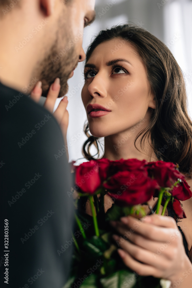 selective focus of attractive girlfriend with bouquet looking at boyfriend in 14 february