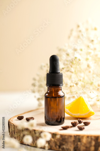 Spa-still life. Moisturizing facial serum with coffee beans  lemon slices and white small flowers on a wooden stand.