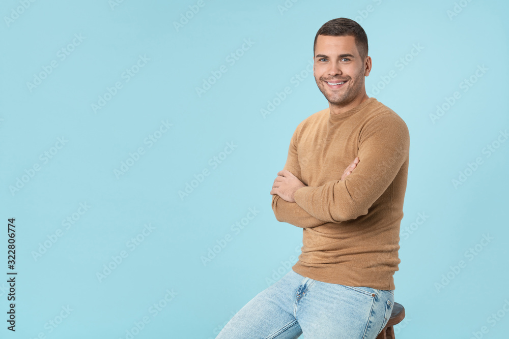 Portrait of handsome young man in casuals sitting on the chair over blue background Portrait of handsome young man in casuals sitting on the chair over blue background