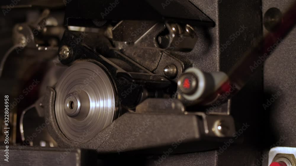 Macro shot of the spinning sprocket wheel and film strip inside a working 16mm vintage projector.