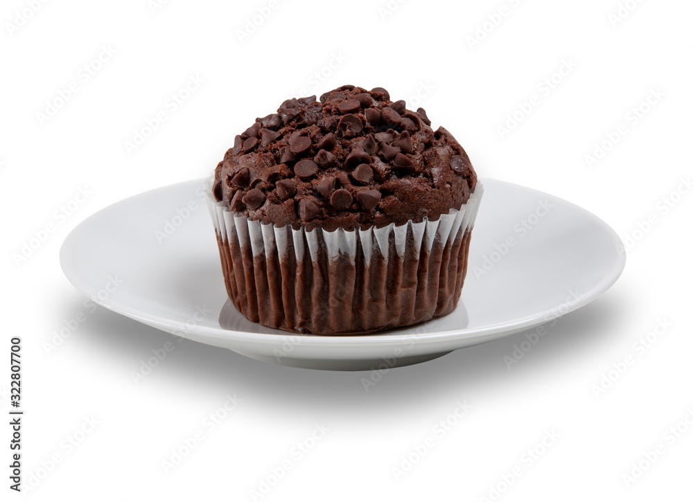 Chocolate muffin with choc chips on the top on a white plate, shot on a white background Chocolate muffin with choc chips on the top on a white plate, shot on a white background