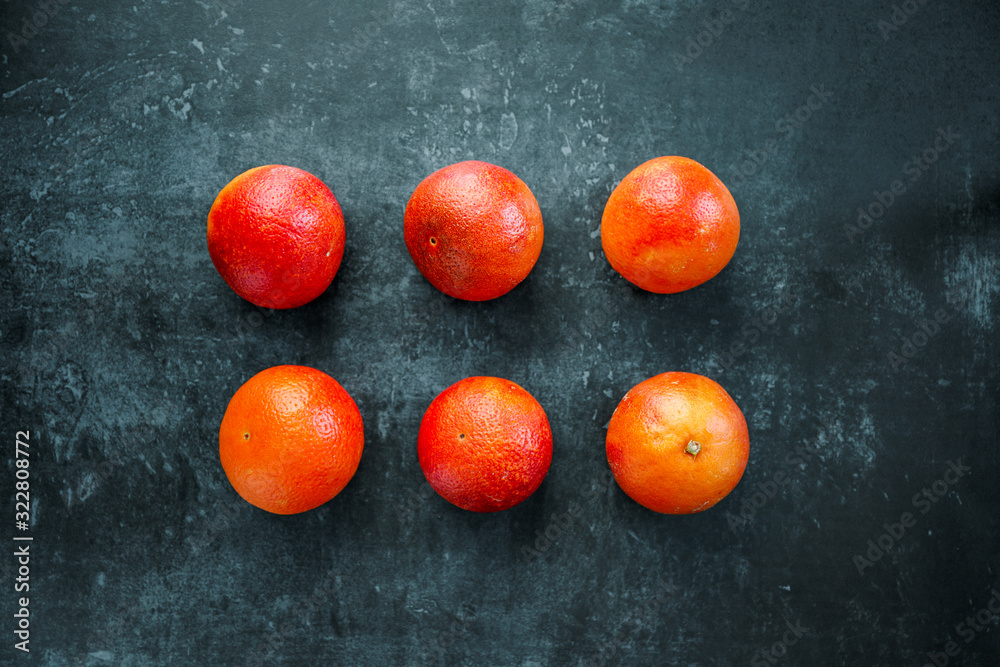Six blood oranges on a dark blue background, flat lay food composition, top view. Six blood oranges on a dark blue background, flat lay food composition, top view.