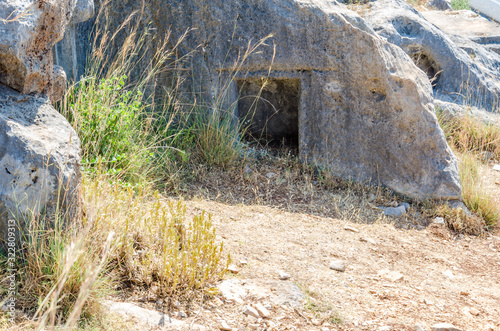 Ancient cemetery in the city of Limyra, Turkey. The entrance to the old concrete tomb in the rock. Excursion to the historical monument of architecture. Burial of ancestors closer to the sky photo