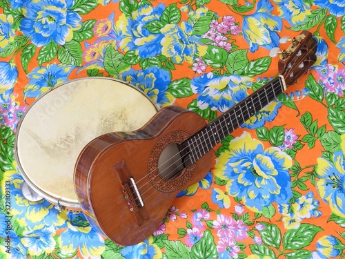 Two Brazilian musical instruments: cavaquinho and pandeiro (tambourine) on a very colorful “chitao” fabric with large floral prints. They are widely used to accompany samba and choro music.
