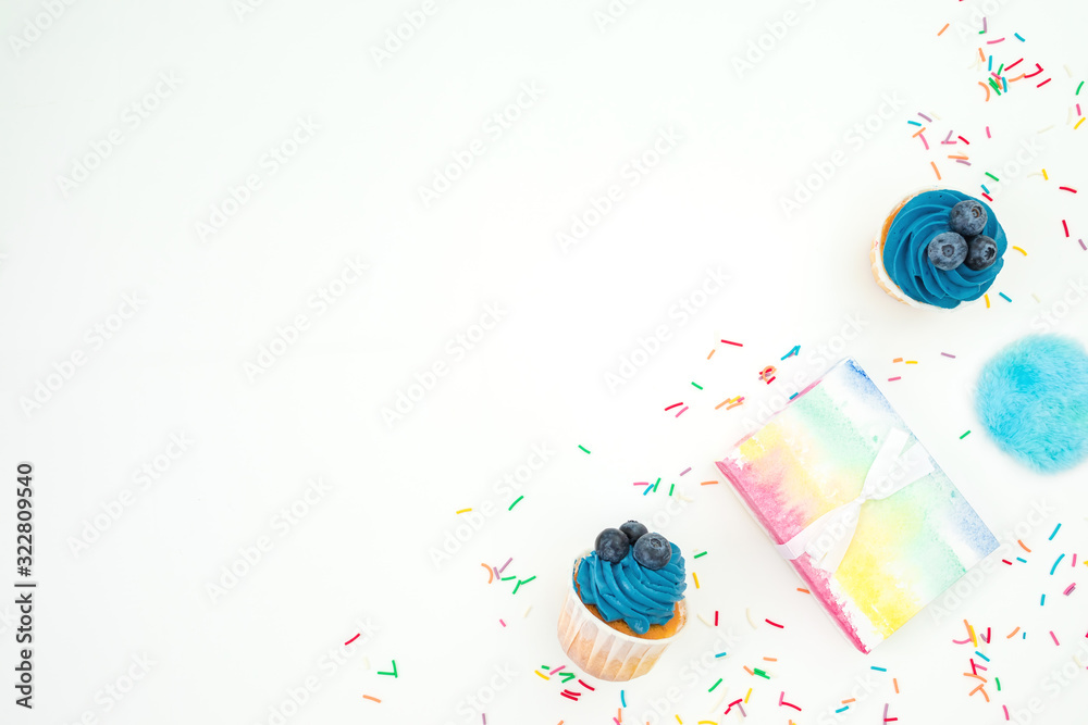 Blueberry muffins with cream and rainbow card on white background. Flat lay, top view