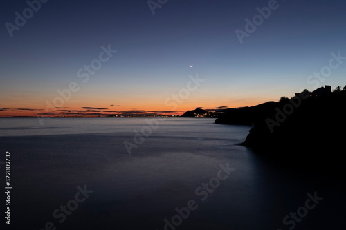 Beautiful and romantic sunset by the mediterranean sea with the San juan beach in the horisont skyline. Long exposure image. 