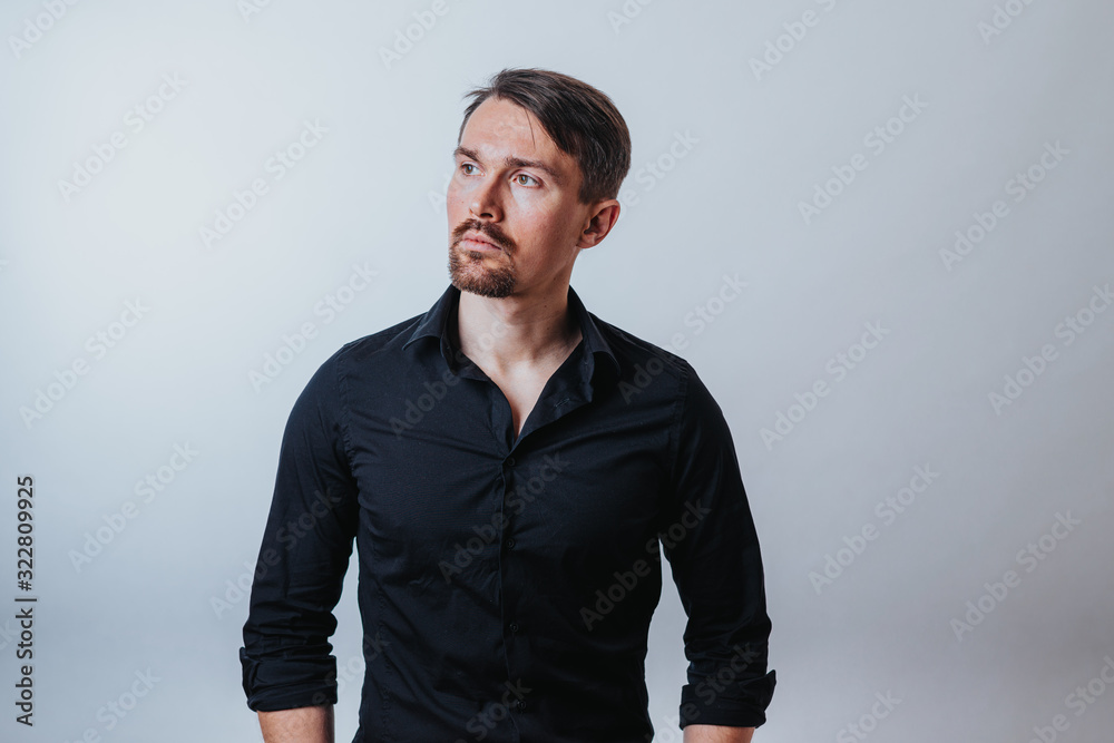 Photo of a handsome man with a coolly stylized scrub and hairstyle. Photo taken in a photo studio on a gray background. The man tries to express his emotions with gesticulation and mimics. Photo of a handsome man with a coolly stylized scrub and hairstyle. Photo taken in a photo studio on a gray background. The man tries to express his emotions with gesticulation and mimics.