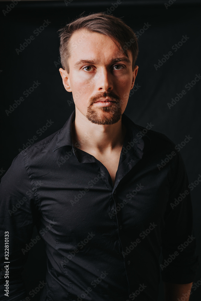 Handsome man. Photo in a photo studio on a black background. A young man expresses his emotions with expressions, gesticulation and attitude.