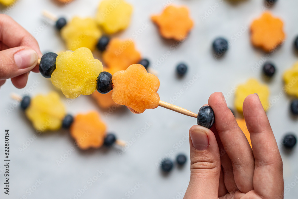 Fruits kebab including blueberry, yellow watermelon and cantaloup with marble background