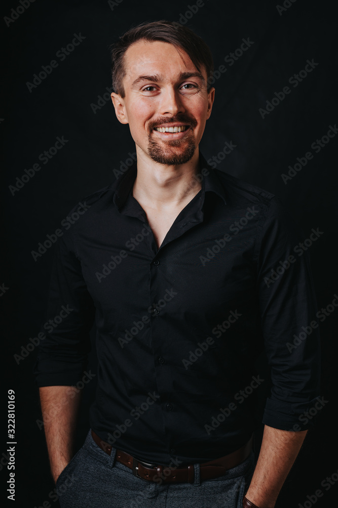 Handsome man. Photo in a photo studio on a black background. A young man expresses his emotions with expressions, gesticulation and attitude.