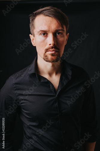 Handsome man. Photo in a photo studio on a black background. A young man expresses his emotions with expressions, gesticulation and attitude.