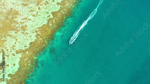 Aerial: flying over longboat moored in water on tropical island , thailand photo