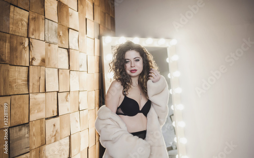 Sexy brunette woman posing in elegant lingerie and fur posing in studio