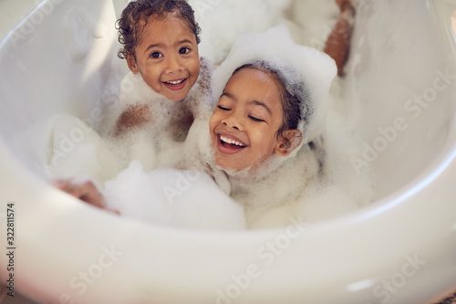 Portrait playful sisters enjoying bubble bath
