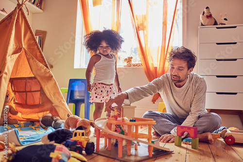 Father and daughter playing with toys on floor photo