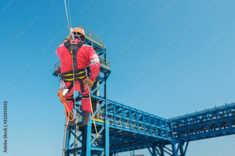 worker at hight, aerial view of an abseiler wearing prosonal protective Equipment  ( PPE ) hanging at structure pipe line platform