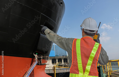 Engineering, foreman with walkies- talkie hand finger pointing operatete control worker painting on hull on floating dry dock in shipyard photo