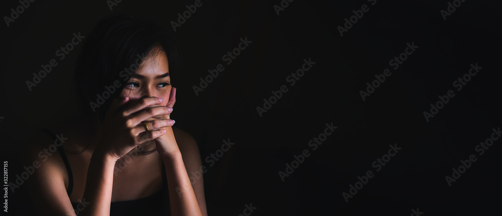 Sad depressed woman suffering from family life. women sitting in dark room and right palm touching her face feeling worry. Young beautiful women thinking how to solve problem.