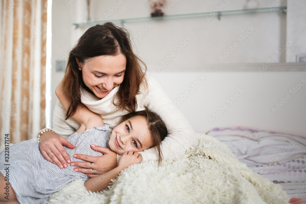 Tender Caucasian mom and daughter hugging on bed Tender Caucasian mom and daughter hugging on bed