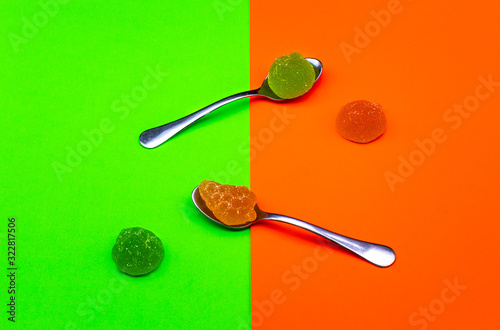 Fondo verde y naranja con cucharas y golosinas.