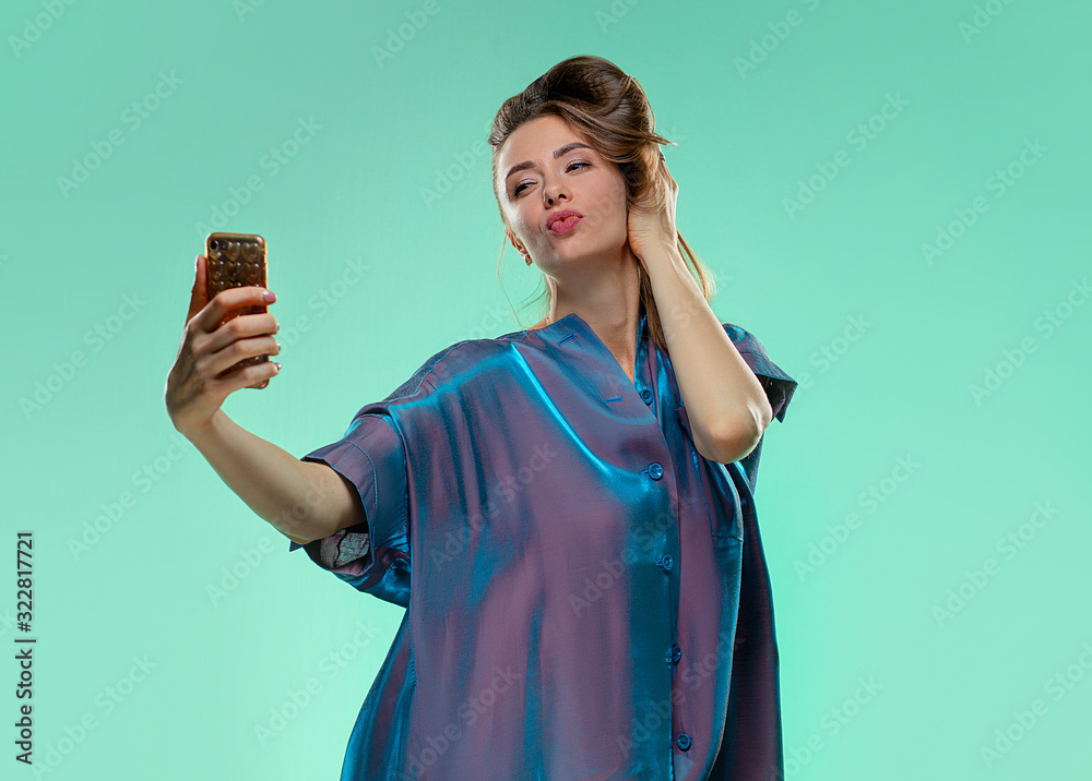 Funny girl with brunette hair makes selfie and grimaces on green background. Studio photo. Lifestyle concept. Funny girl with brunette hair makes selfie and grimaces on green background. Studio photo. Lifestyle concept.
