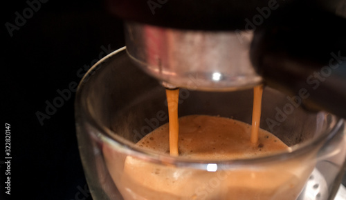 The coffee maker. Close shot. Coffee in a double-walled glass cup. Coffee is poured from a coffee machine in the morning