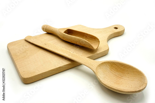 Wooden kitchen utensils on white background. Cutting board, spoon and scoop.