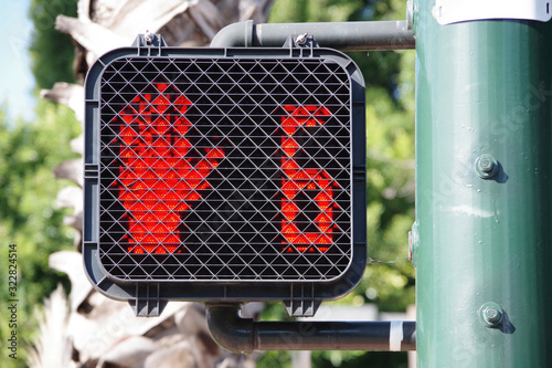 Pedestrian crosswalk traffic signal at a city intersection with a red hand warning to not enter because only six seconds left for crossing photo