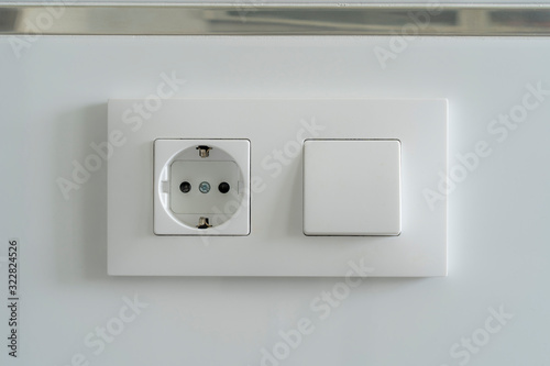 Enchufe e interruptor en pared blanca de azulejo.