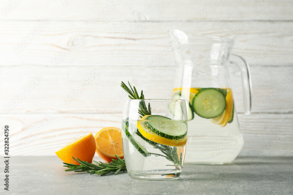 Jug and glass with cucumber water on grey table, close up - obrazy, fototapety, plakaty 