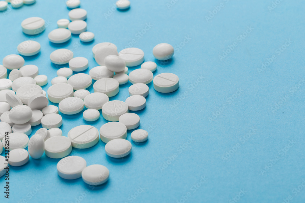 scattered white pills on a blue table. Layout for special offers such as advertising or other ideas. The concept of medicine, pharmacy and healthcare. Space for copy. flat lay for text or logo. scattered white pills on a blue table. Layout for special offers such as advertising or other ideas. The concept of medicine, pharmacy and healthcare. Space for copy. flat lay for text or logo.