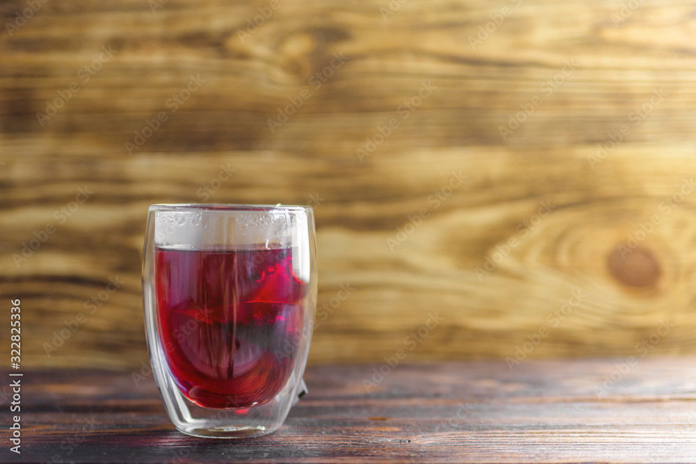 glass Cup with red fragrant tea brewed in a bag on a wooden background copy space. red useful tea for colds and flu glass Cup with red fragrant tea brewed in a bag on a wooden background copy space. red useful tea for colds and flu