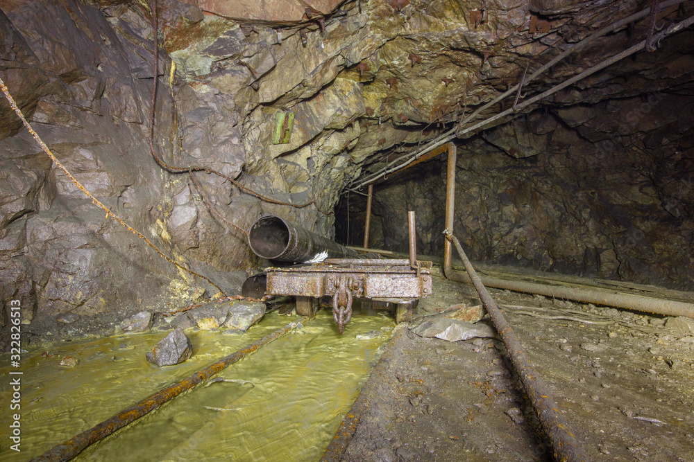 Naklejka premium Old copper mine underground tunnel with rails and cart
