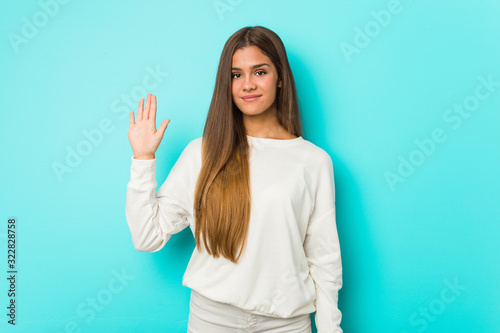 Young slim woman smiling cheerful showing number five with fingers.