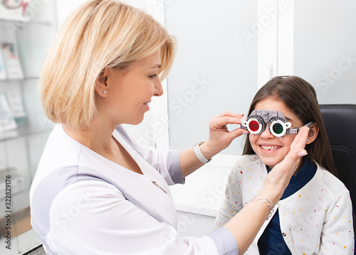 Child with optometrist trial frame in vision clinic. Optometrist helping select glasses for treatment of vision