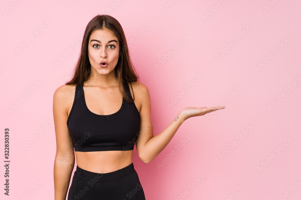 Φωτογραφία Young caucasian fitness woman doing sport isolated impressed holding copy space on palm