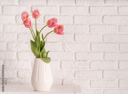 White vase with bouquet of beautiful tulips on brick wall background