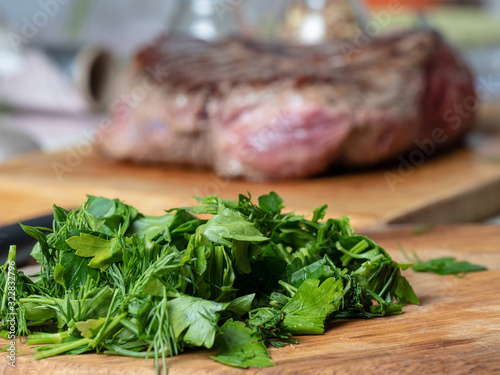 Fresh chopped greens in the foreground and a piece of meat blurred in the background. Concept of food and proper nutrition photo