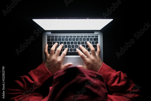 hooded hacker hand stealing data from laptop 