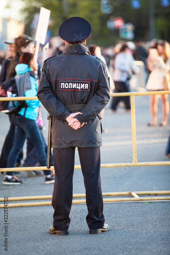 Police officer is on guard at the Victory Day celebration in the World War II. Rear view, full length. Saint-Petersburg, Russia. Text is on back in Russian: police