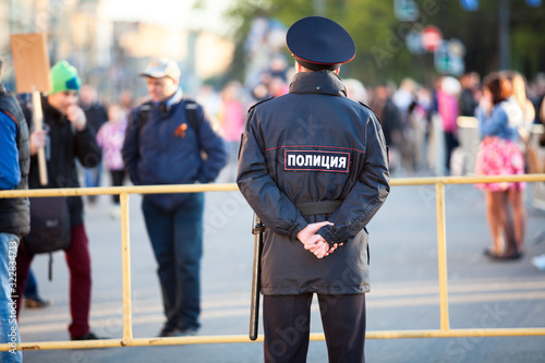 Police officer is on guard at the Victory Day celebration in the World War II. Rear view. Saint-Petersburg, Russia. Text is on back in Russian: police