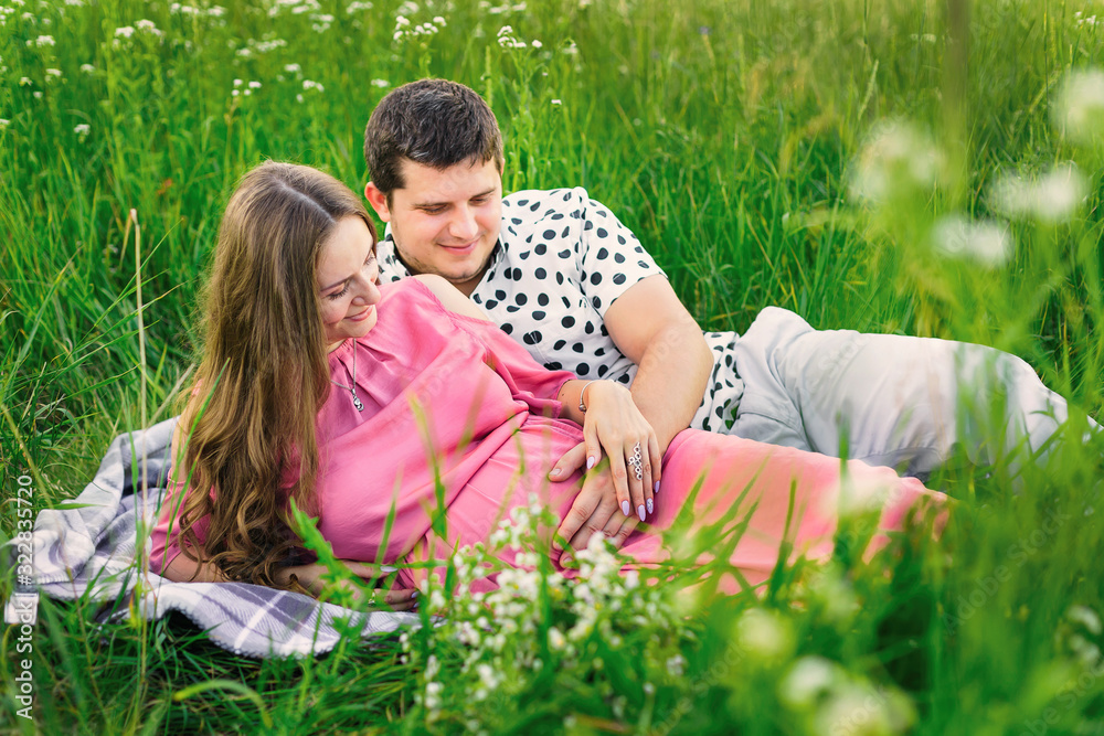 man and woman lie on a blanket among tall grass and gently touch man and woman lie on a blanket among tall grass and gently touch